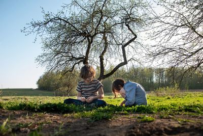 Rear view of two kids sitting on field