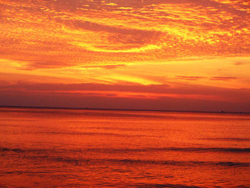 Scenic view of sea against dramatic sky during sunset