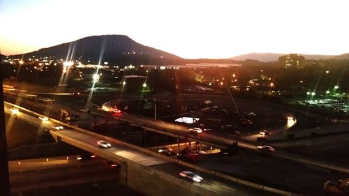 Illuminated road by city against sky at night