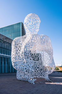 Statue against building in city against clear sky