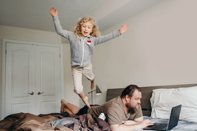 Work from home with kids children. father working on laptop in bedroom with child daughter 