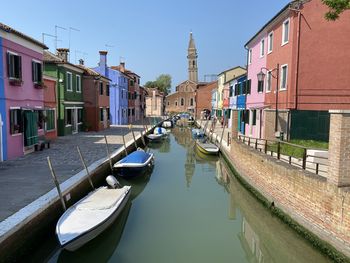 Boats moored on canal against buildings in city