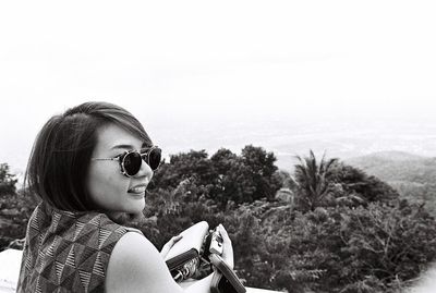 Close-up of young woman in sunglasses against clear sky