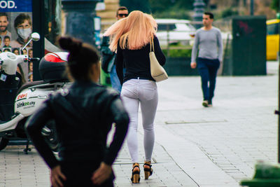 Rear view of people walking on street in city