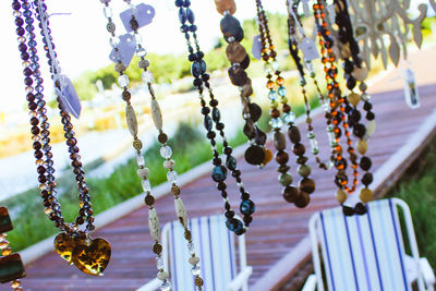 Close-up of various necklaces hanging against boardwalk