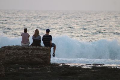 Rear view of people looking at sea against sky