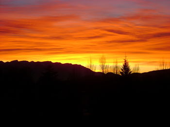 Scenic view of silhouette mountains against orange sky