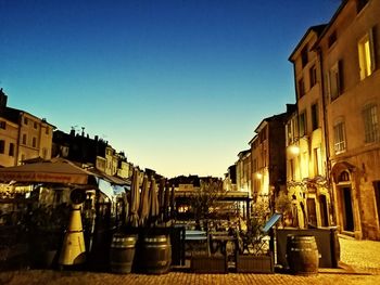 Street amidst buildings against clear blue sky at dusk