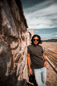 Portrait of man wearing sunglasses while standing by wall