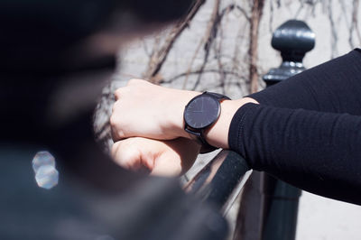 Cropped image of hand wearing wristwatch while holding railing