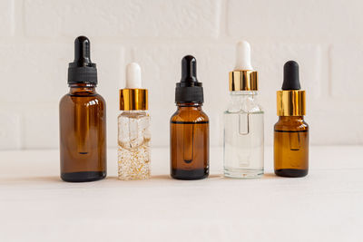 Dark glass and transparent cosmetic bottles with face serum or essentioal oil on a wooden background