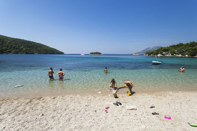 People on beach against clear sky