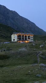 House on field by mountain against sky