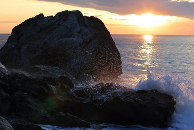 Scenic view of rocks in sea against sky during sunset