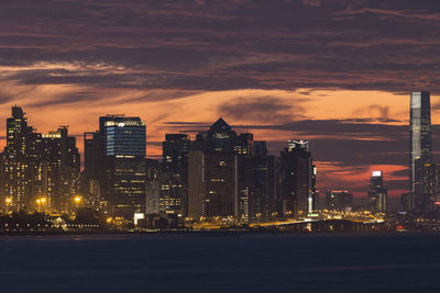 Illuminated buildings in city against sky during sunset