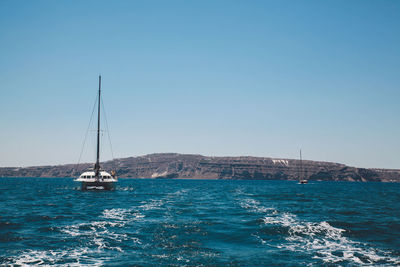 Boat sailing in blue sea against clear sky on sunny day