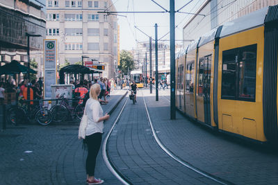 Side view of woman standing on street by tramway