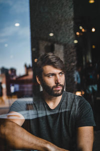 Portrait of young man looking away while sitting in cafe