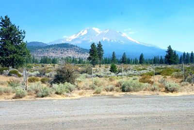 Scenic view of field by mountains against blue sky