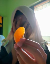 Close-up of woman holding orange slice