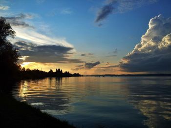 Scenic view of lake against cloudy sky during sunset