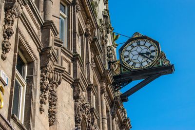 Low angle view of clock tower against blue sky