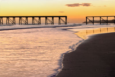 Pier over sea against sky during sunset