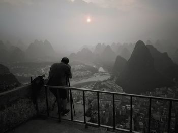 Rear view of man looking at mountains against sky