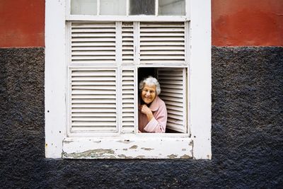 Portrait of happy boy against window of building