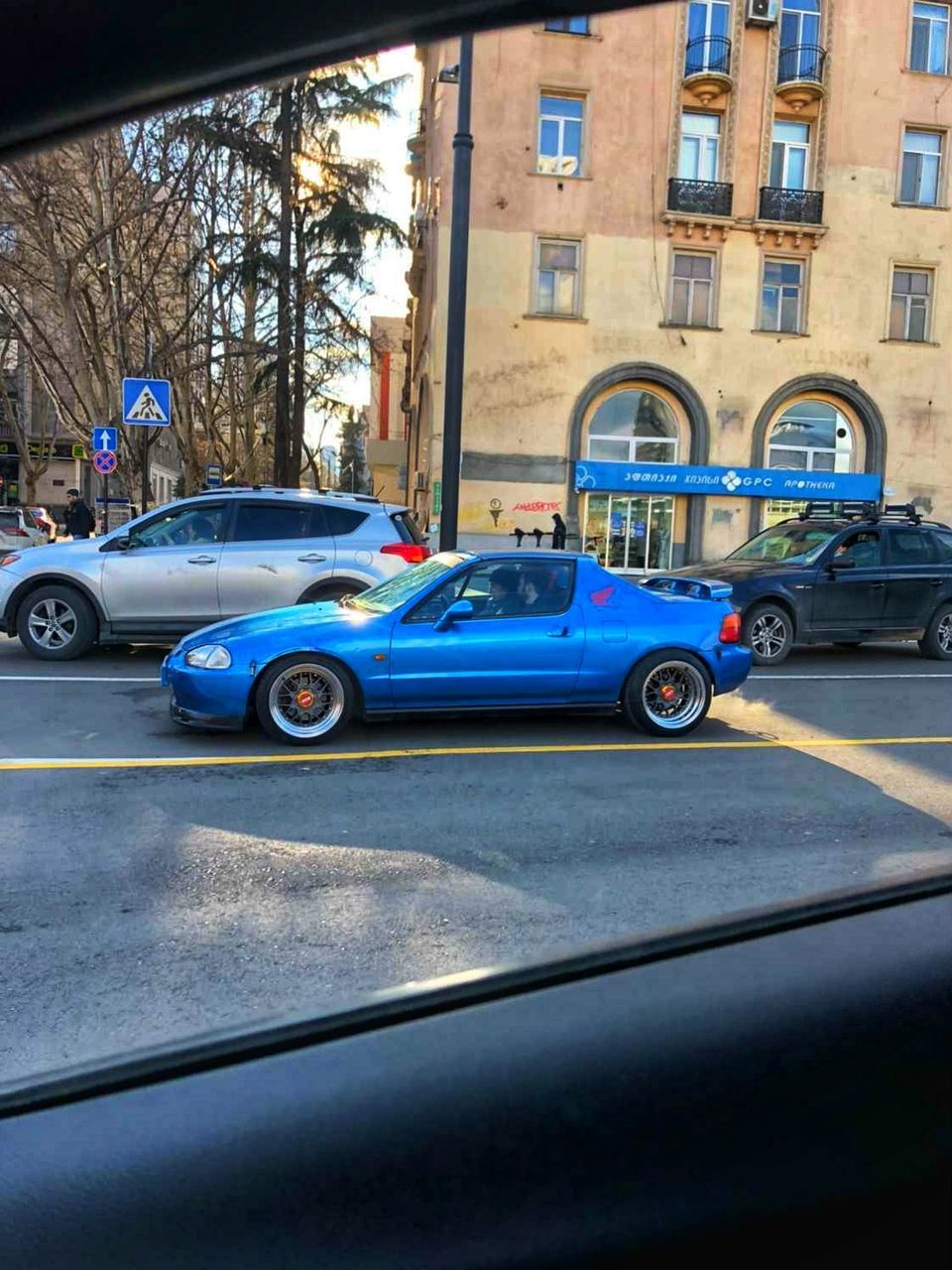 mode of transportation, car, motor vehicle, transportation, land vehicle, architecture, vehicle, built structure, city, building exterior, street, automobile, road, day, sports car, supercar, no people, tree, vintage car, luxury vehicle, travel, blue, window, outdoors, city life, on the move