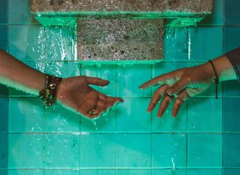 Cropped image of wet hands by wall