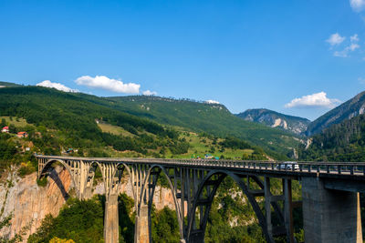 Arch bridge over mountains against sky