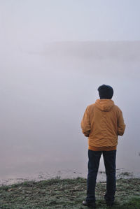 Rear view of man standing by sea against sky