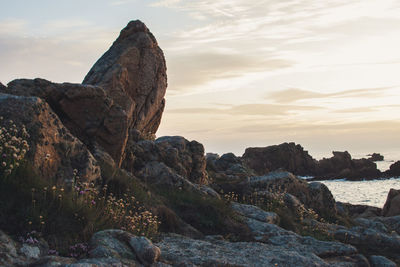 Rock formation on beach against sky during sunset