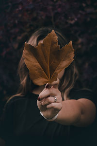 Close-up of woman holding maple leaf during autumn