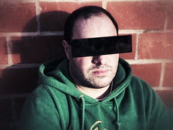 Portrait of man wearing 3-d glasses against brick wall