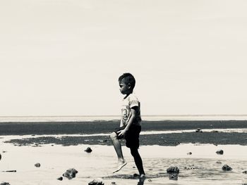 Full length of woman standing on beach against clear sky