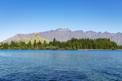 Scenic view of lake and mountains against clear blue sky