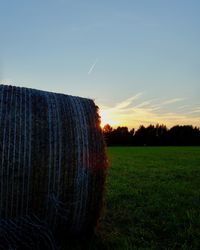 Hay bales on field against sky during sunset