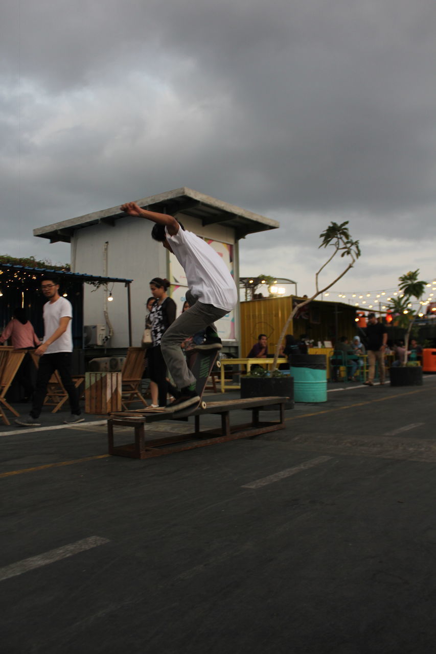 PEOPLE ON STREET AGAINST SKY IN CITY AT DUSK