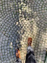 Low section of man walking on cobblestone