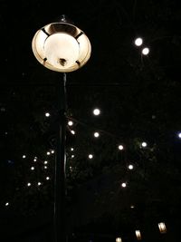 Low angle view of illuminated light bulb hanging at night