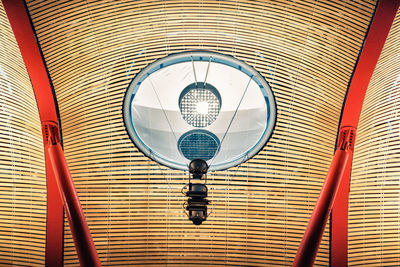 Low angle view of electric lamp hanging on ceiling of building