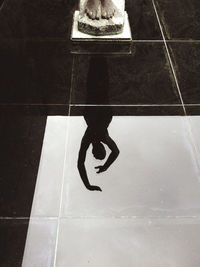 Black and white of statue of female with raised arms reflecting in tiled floor in barcelona city