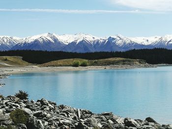 Scenic view of lake by snowcapped mountains against sky