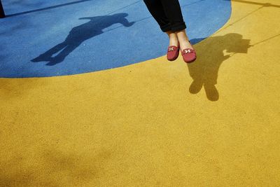 Low section of woman standing on yellow shadow