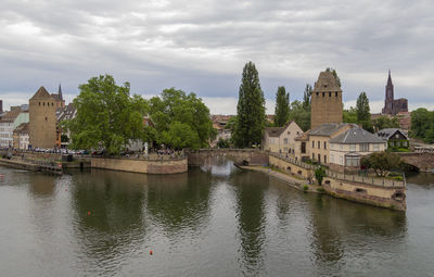 Buildings by river against sky