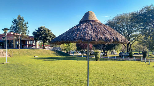 Thatched roof parasol in park against clear sky