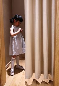 Cute girl standing by curtain in changing room