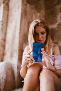 Worried blonde woman sitting and looking her mobile phone in majorca